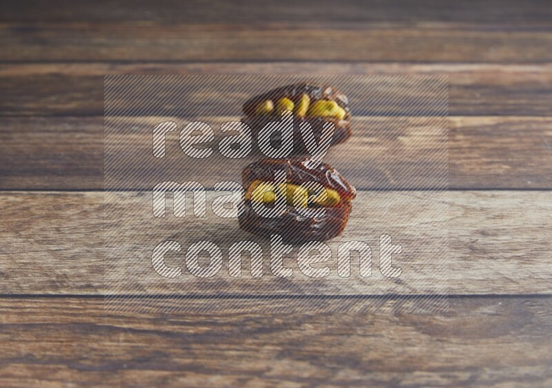 two pistachio stuffed madjoul date on a wooden background