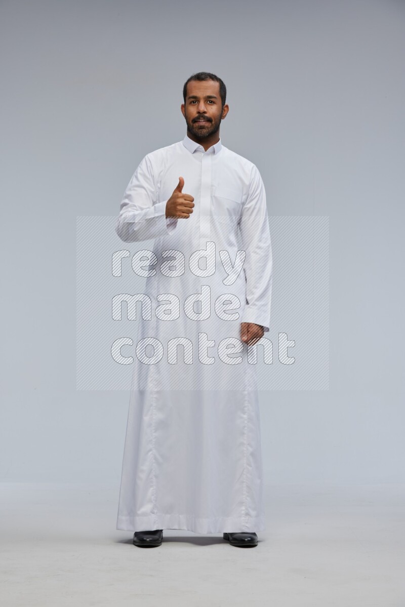 Saudi man Wearing Thob standing interacting with the camera on Gray background