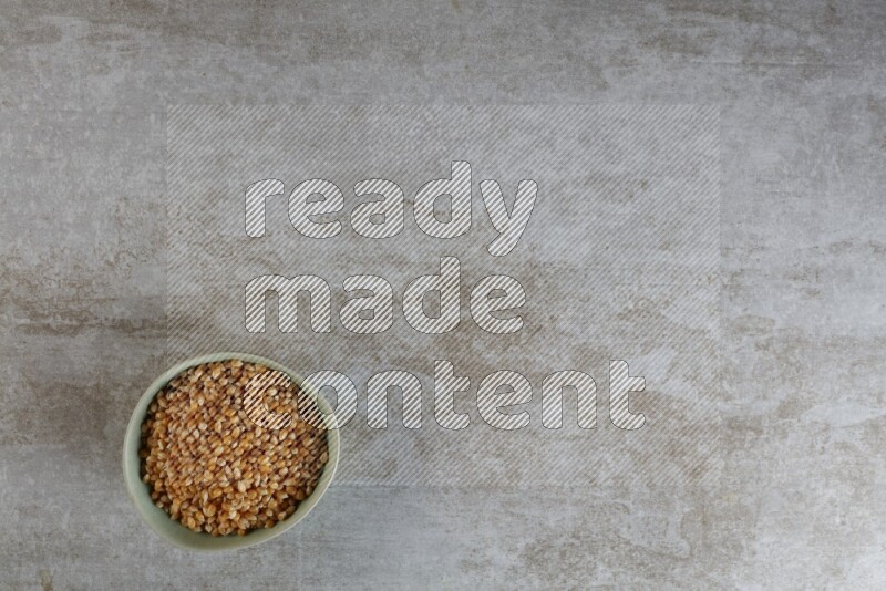 corn kernel in a green ceramic bowl on a grey textured countertop