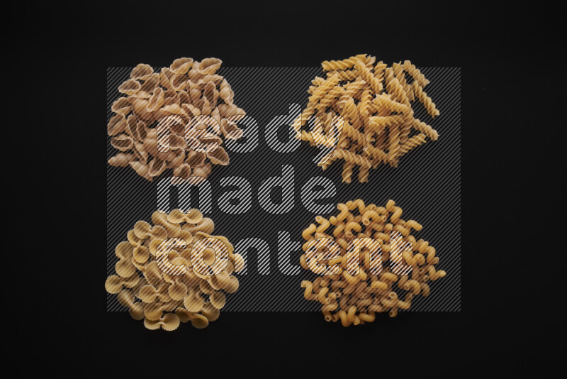 Different pasta types in bunches on black background