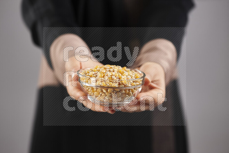 Woman in abaya holding different kinds of legumes in different positions