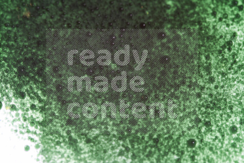 Close-ups of abstract green watercolor drops on oil Surface on white background