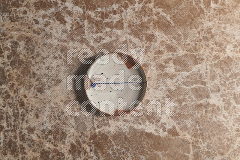 A multicolored pottery plate on beige marble background