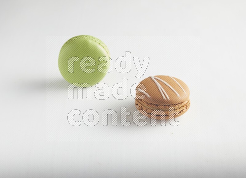 45º Shot of of two assorted Brown Irish Cream, and Green Pistachio macarons on white background