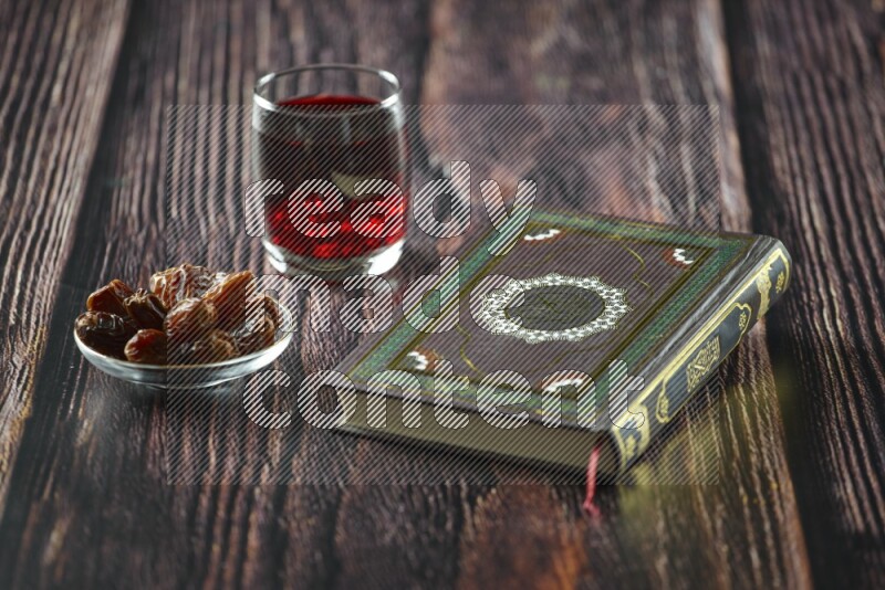 Quran with dates, prayer beads and different drinks all placed on wooden background