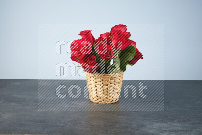 Vibrant red roses in a wicker basket on black marble background