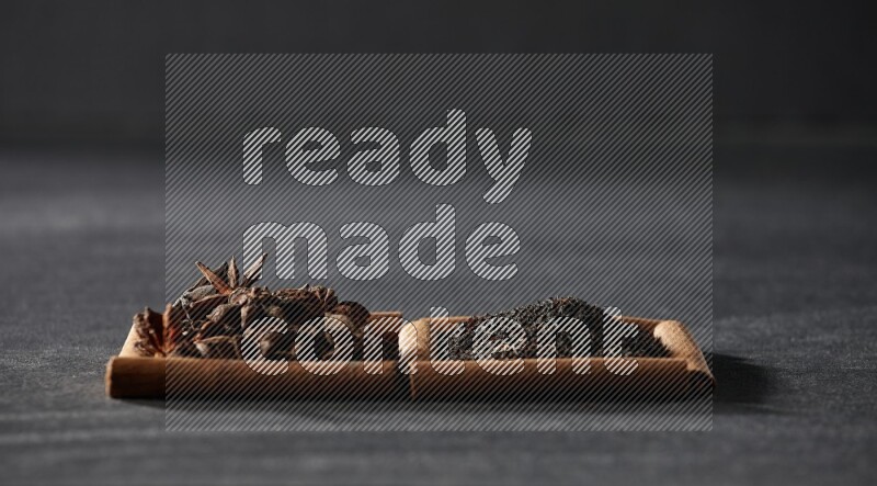 2 squares of cinnamon sticks full of star anise and black tea on black flooring
