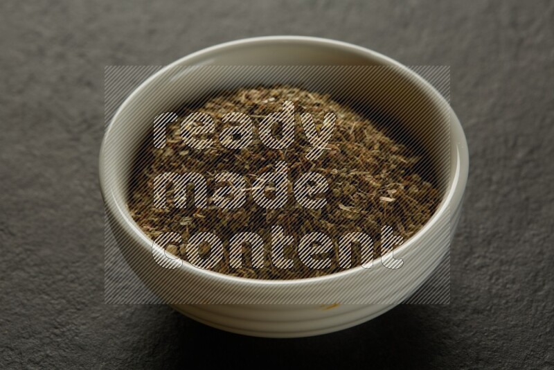 wooden round sauce bowl filled with herbs on grey textured countertop