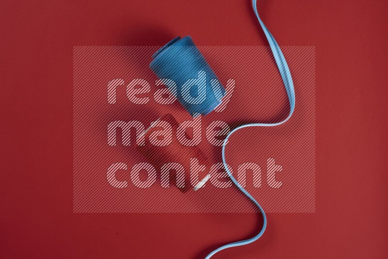 A blue and red collection of sewing and tailoring tools arranged on a red background