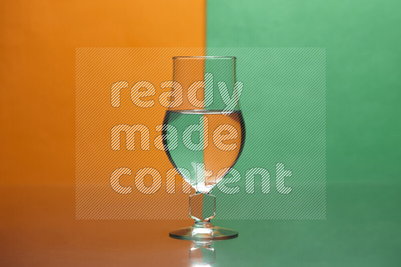 The image features a clear glassware filled with water, set against orange and green background