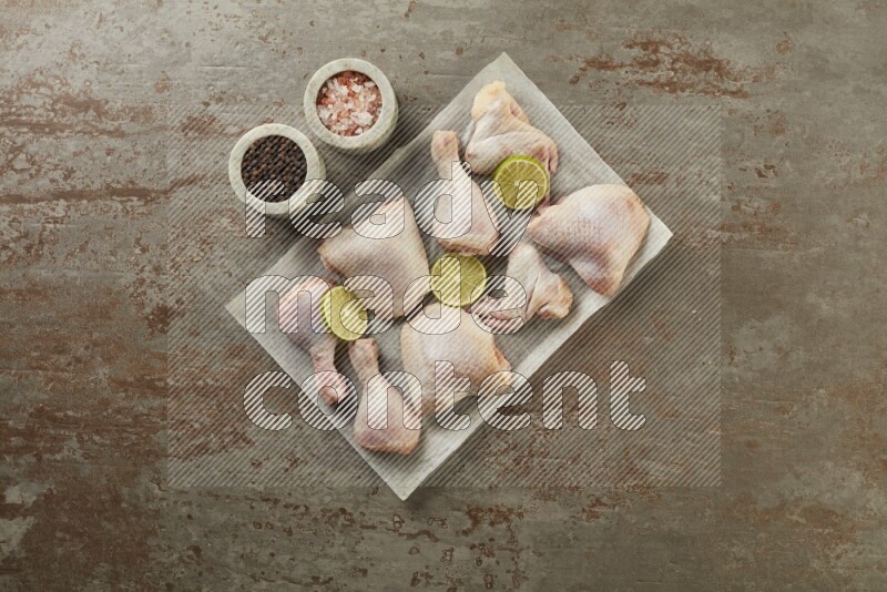 Mixed fresh chicken pieces on a parchment paper direct on a textured rustic background