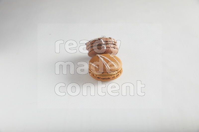 45º Shot of of two assorted Brown Irish Cream, and Brown white Chocolate Caramel macarons on white background