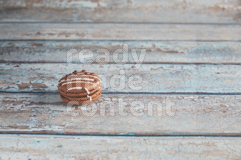 45º Shot of Brown white Chocolate Caramel macaron on light blue wooden background