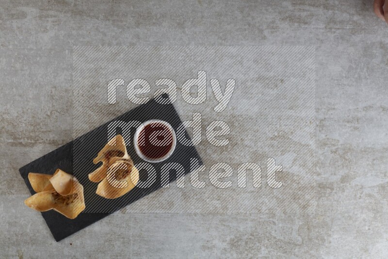 wonton cups with soy sauce ramkin on rectangle slate on grey textured counter top