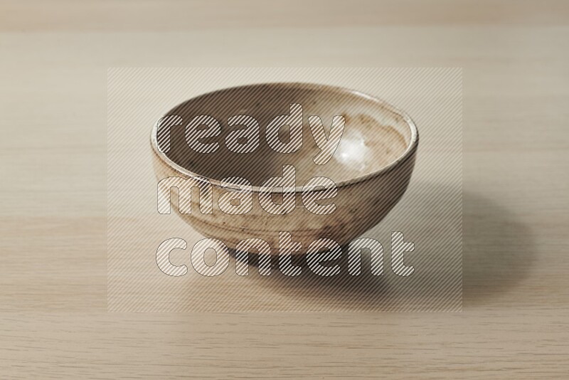 A beige pottery bowl on light wooden background