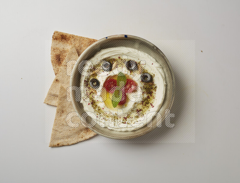 Lebnah garnished with cherry tomato, mint, olives & pine nuts in a grey pottery plate on a white background