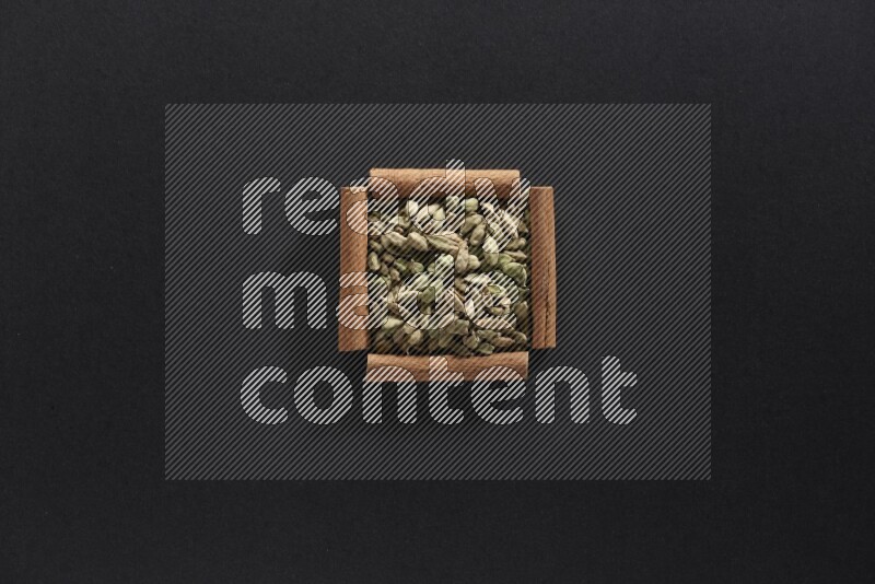 A single square of cinnamon sticks full of Cardamom on black flooring