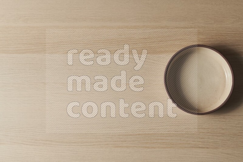 A beige pottery oven bowl on light wooden background