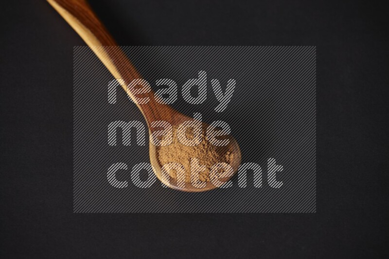 Cinnamon powder in a wooden ladle spoon on black background in different angles