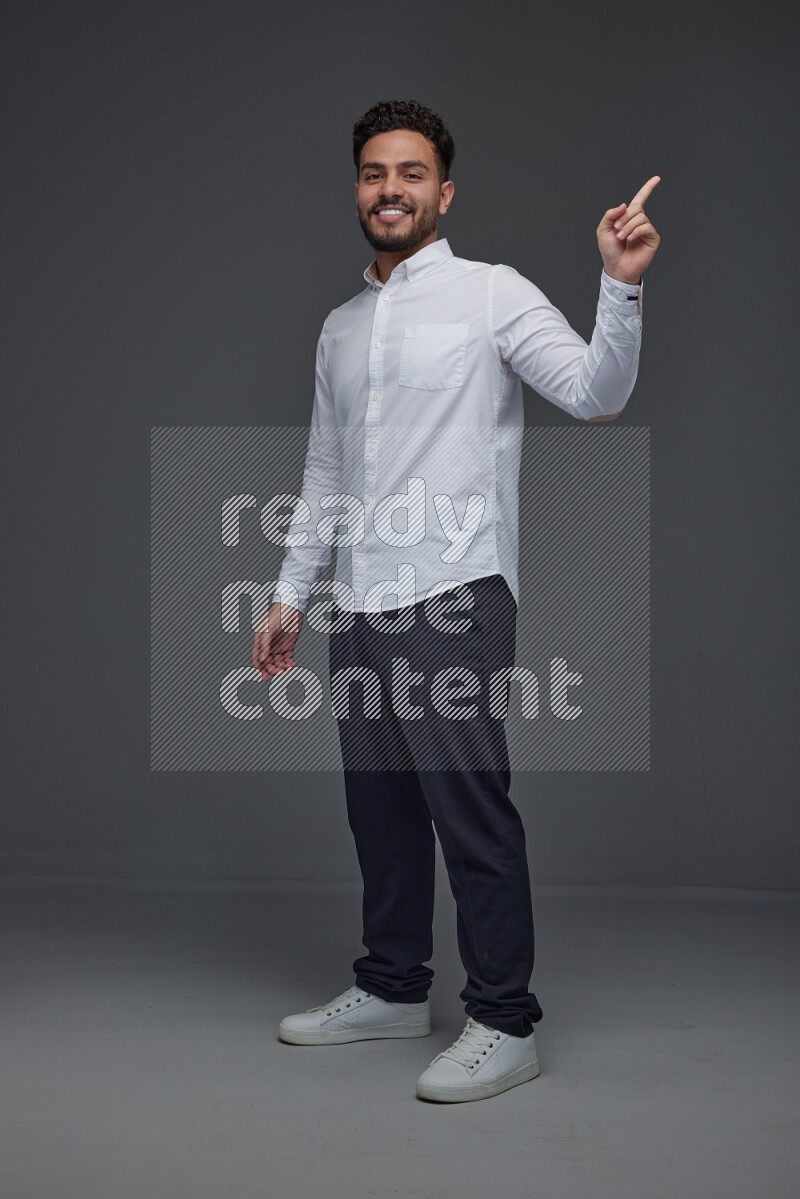 A man wearing smart casual standing and making multi hand gestures eye level on a gray background