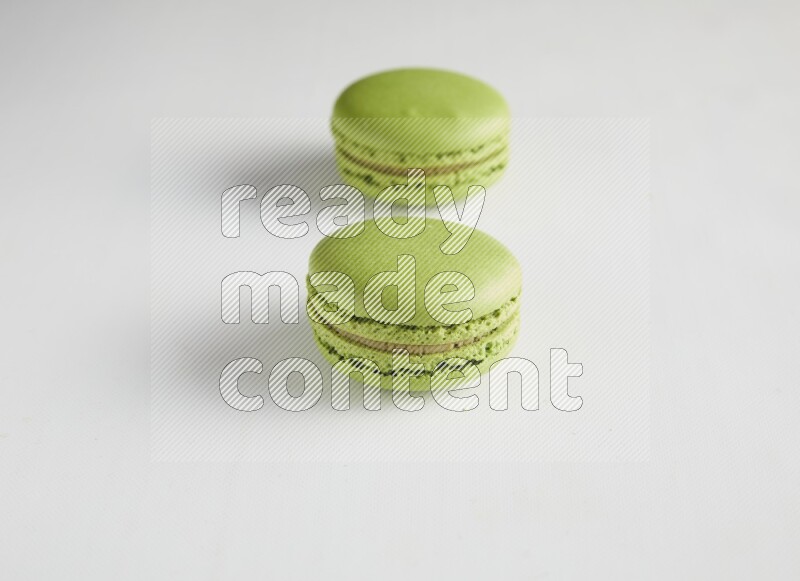 45º Shot of two Green Pistachio macarons on white background