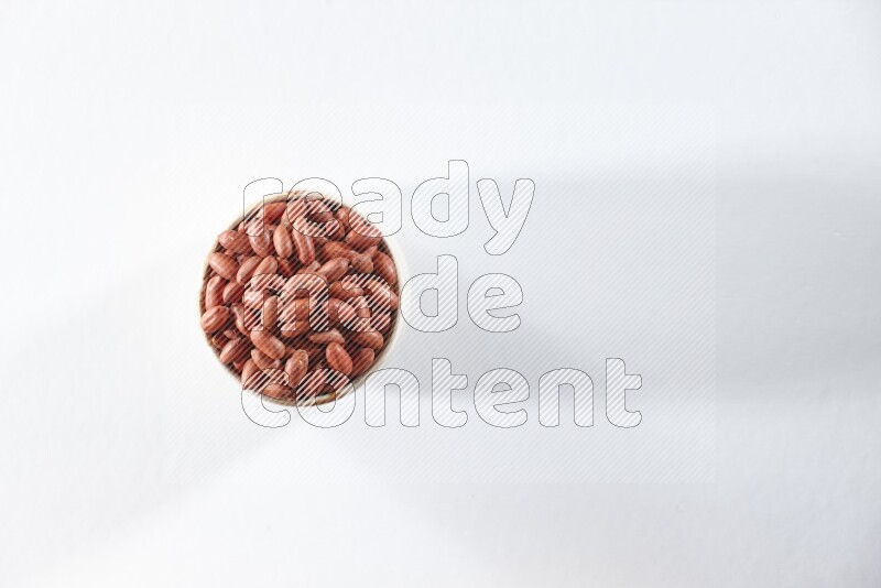A beige ceramic bowl full of red skin peanuts on a white background in different angles