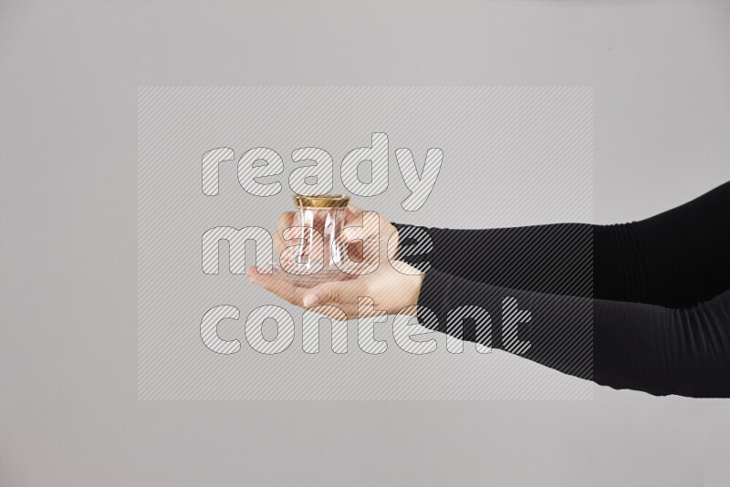 A woman in black abaya holding different glassware in different positions