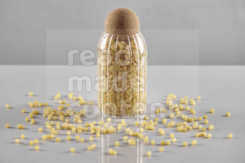 Raw pasta in a glass jar on light grey background