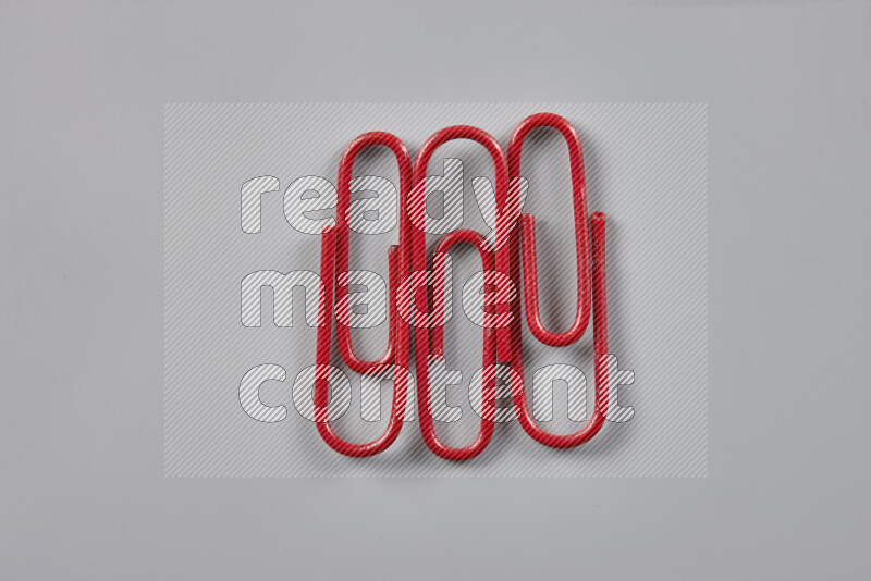 Red paper clips isolated on a grey background