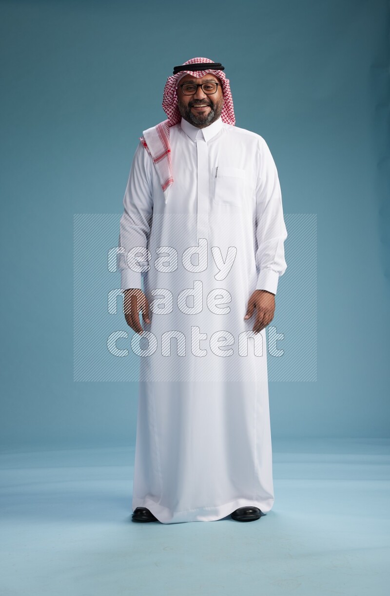 Saudi Man with shimag Standing Interacting with the camera on blue background