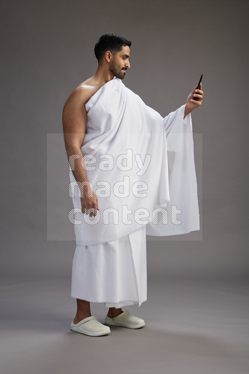 A man wearing Ehram Standing taking selfie on gray background