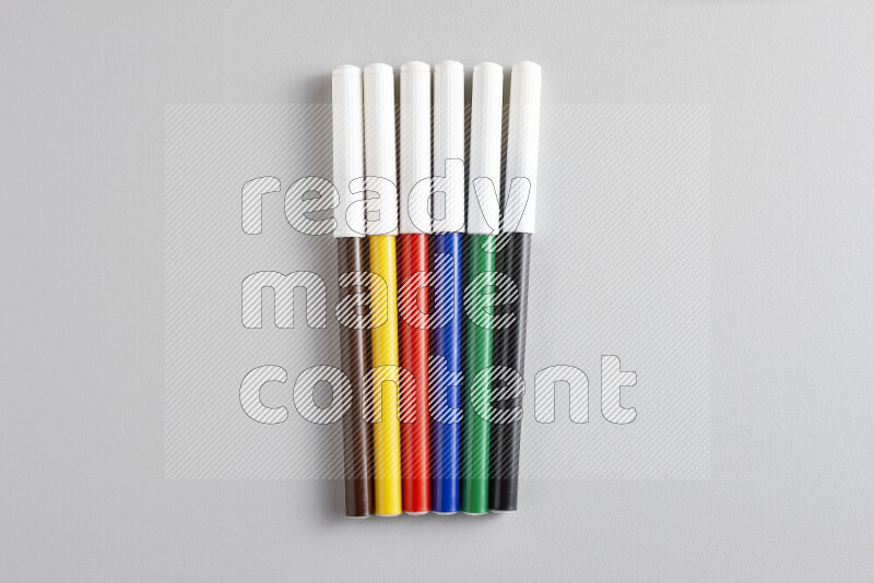 An arrangement of coloring pens in different colors on grey background