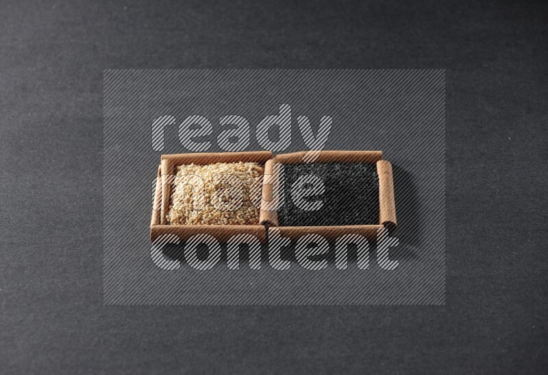 2 squares of cinnamon sticks full of sesame and black seeds on black flooring