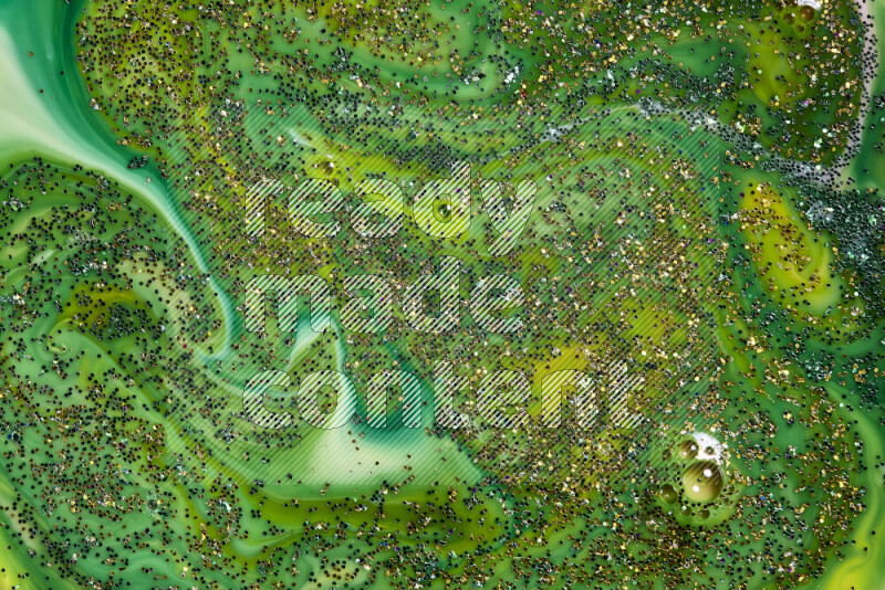 A close-up of sparkling gold glitter scattered on swirling green background