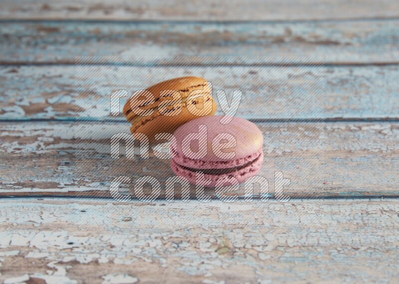 45º Shot of of two assorted Brown Irish Cream, and Purple Strawberry macarons  on light blue background