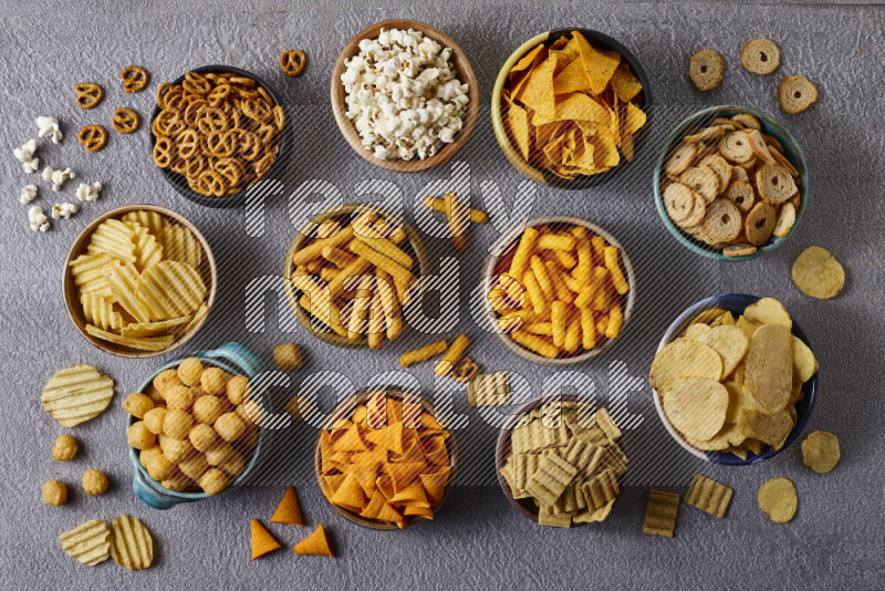 Assorted snacks in pottery bowls on grey background