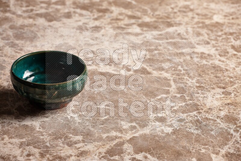 A dark green pottery bowl on beige marble background
