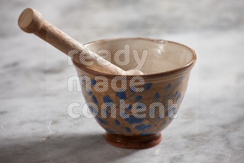 Decorative pottery bowl with wooden honey dipper in it on grey marble background