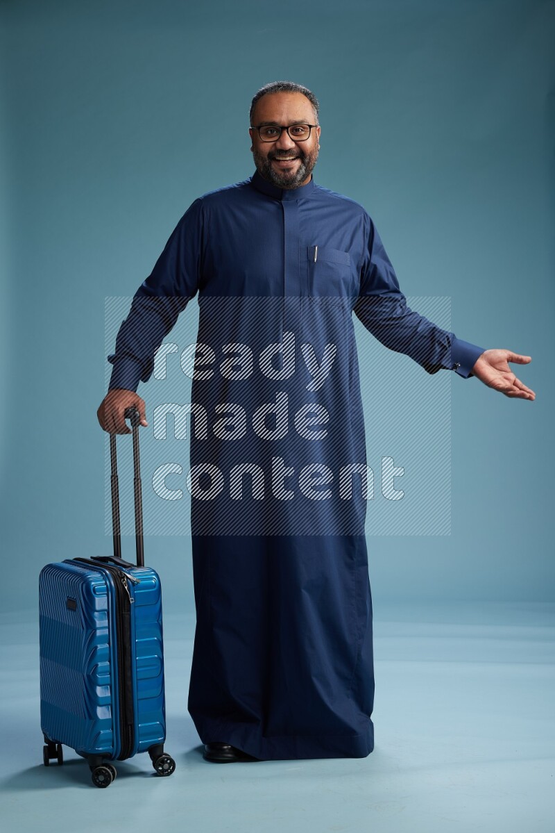 Saudi Man without shimag Standing pulling travel bag on blue background