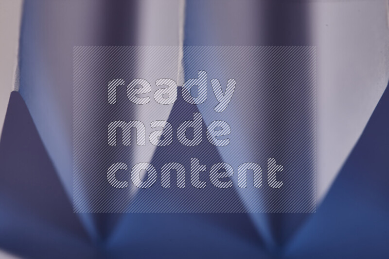 صورة مجردة مقربة تظهر طيات ورقية هندسية حادة بتدرجات اللون الارجواني