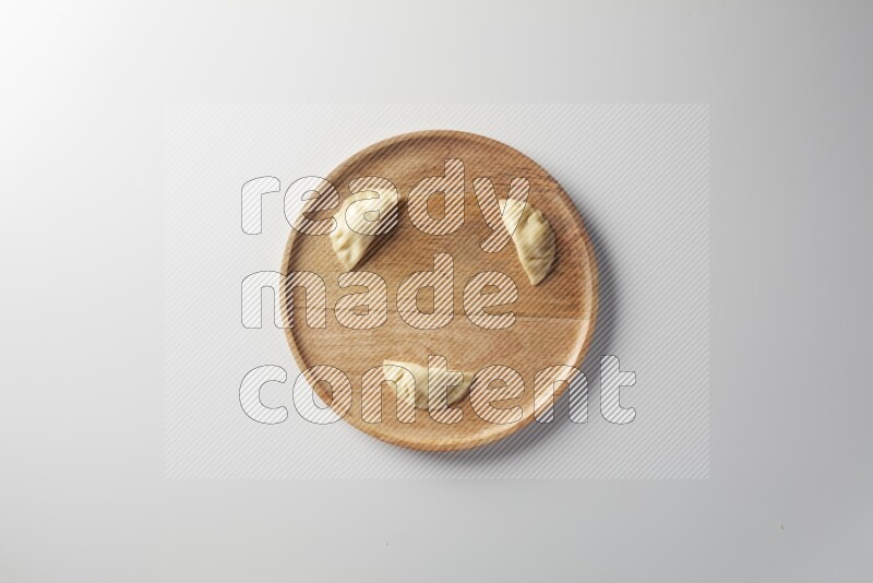 Three Sambosas on a wooden round plate on a white background