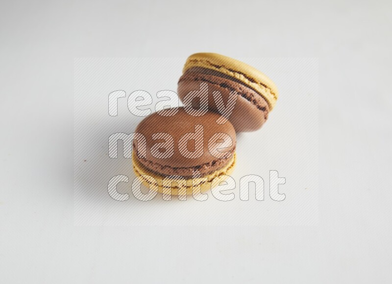 45º Shot of two Yellow and Brown Chai Latte macarons on white background