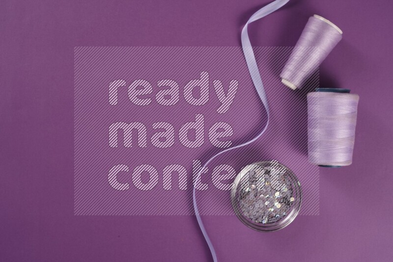 A purple collection of sewing and tailoring tools arranged on a purple background