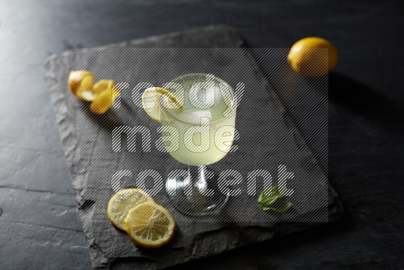A glass of lemon juice with a lemon slice on black background