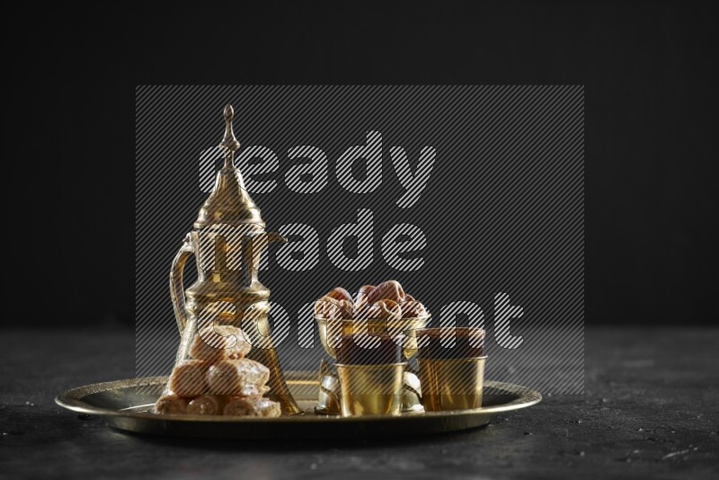 Oriental sweets with dates and a drink on a metal tray in a dark setup