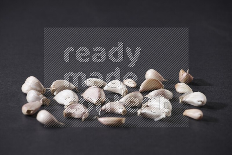 بعض فصوص الثوم متناثرة على أرضية سوداء