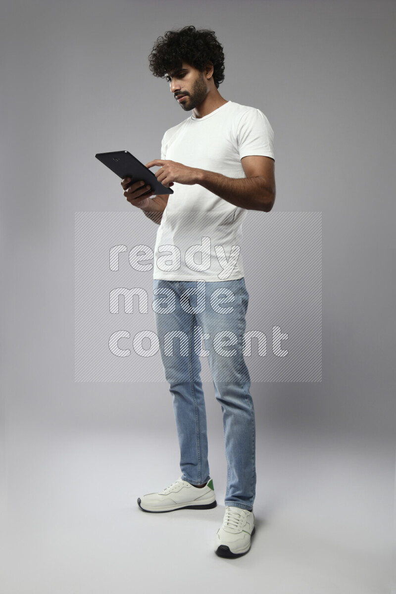 A man wearing casual standing and browsing on a tablet on white background