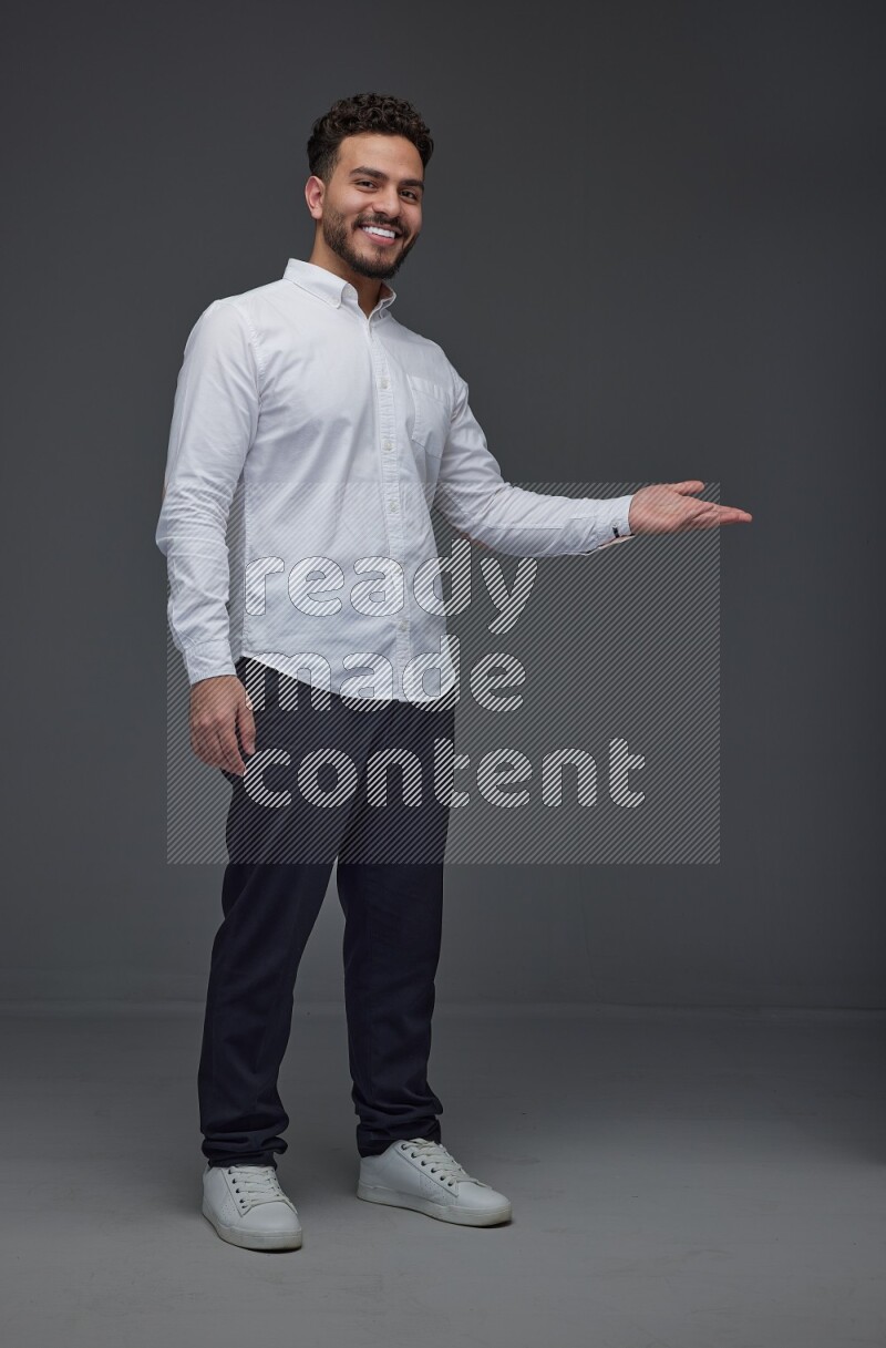 A man wearing smart casual standing and making multi hand gestures eye level on a gray background