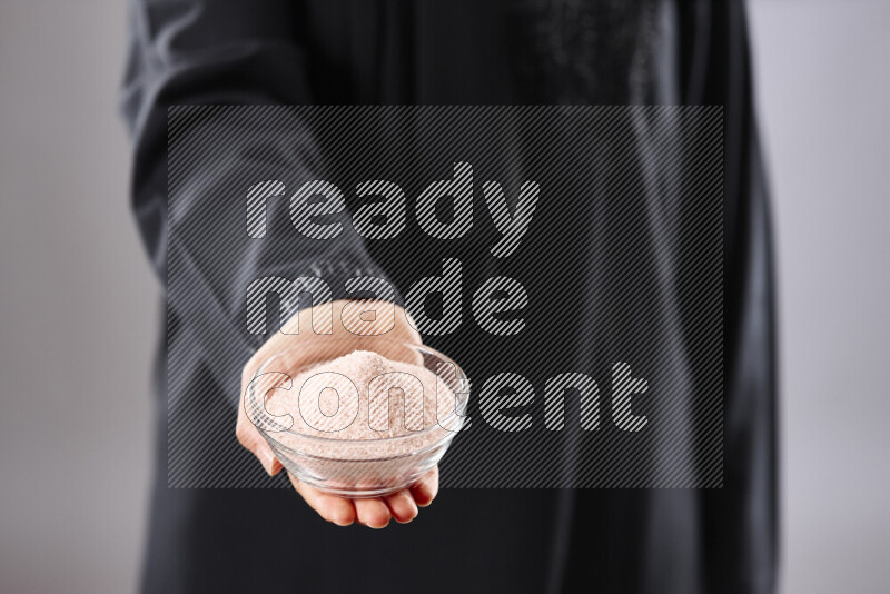 Woman in abaya holding different kinds of spices in different positions