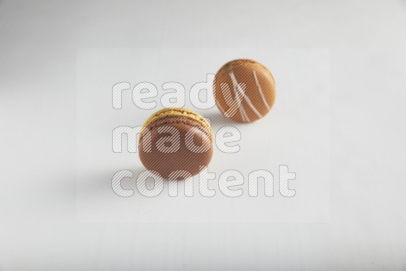 45º Shot of of two assorted Brown Irish Cream, and Yellow, and Brown Chai Latte macarons on white background